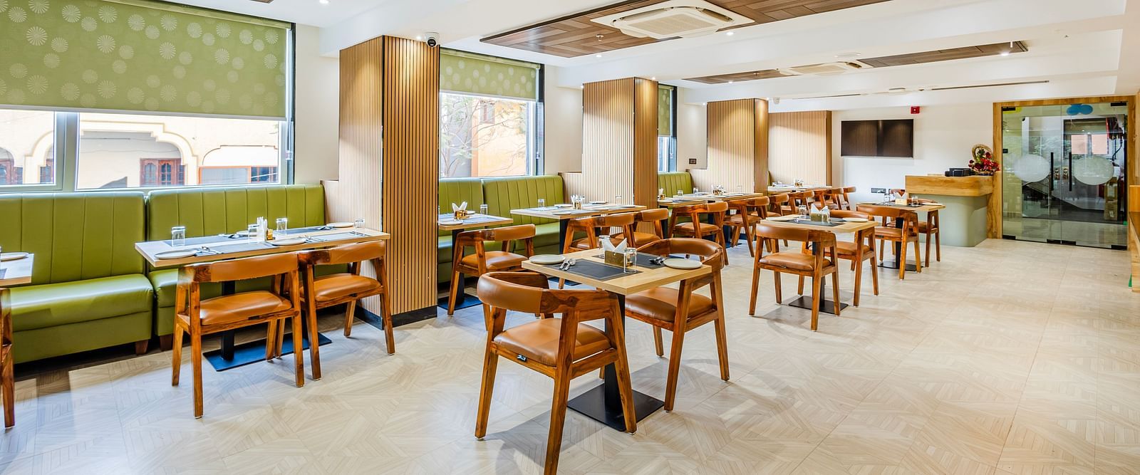 Lemonridge Hotels, KPHB | Dining area with tables and chairs set for meals. Green cushioned booths line the wall.
